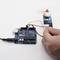 Une main tient un capteur connecté à une carte Arduino. De fins câbles relient les deux composants pour un projet électronique.