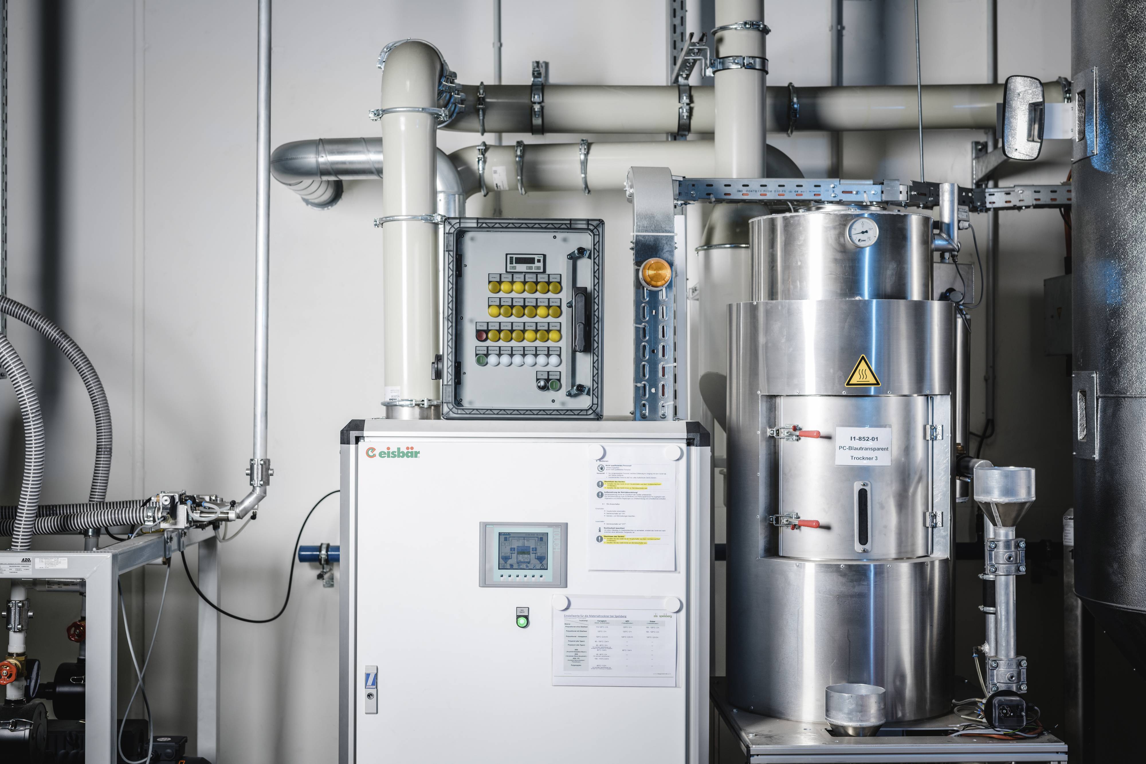 Un espace industriel avec une machine de traitement de l'eau. Des conduites visibles et un panneau de contrôle sur le mur.