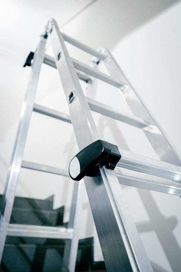 Une échelle métallique est positionnée sur un escalier et est prête à permettre l'accès à des niveaux supérieurs.