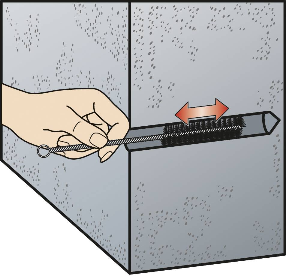 Une main nettoie une grille de ventilation rectangulaire dans un mur avec une longue brosse étroite. Une flèche indique le sens du nettoyage.