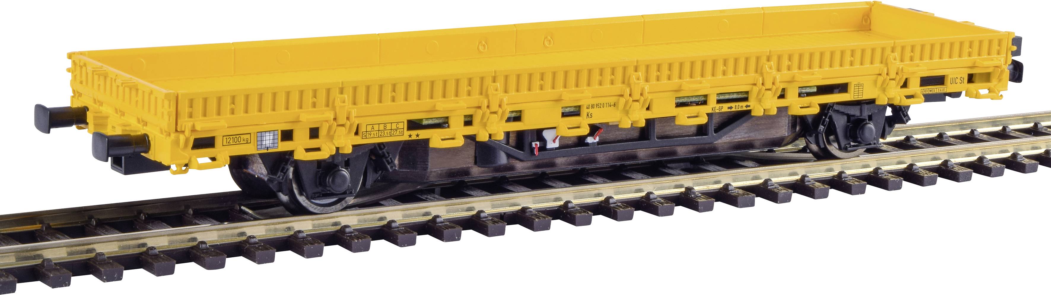Wagon de marchandises jaune sur des rails pour le transport de marchandises lourdes, sans cargaison visible, sur une voie ferrée brune.