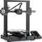 Une imprimante 3D avec un cadre carré et une plateforme d'impression en dessous. Un écran avec des commandes est visible à droite.