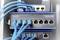 Un commutateur Gigabit industriel à 8 ports avec plusieurs câbles Ethernet bleus branchés, installé dans un rack serveur.