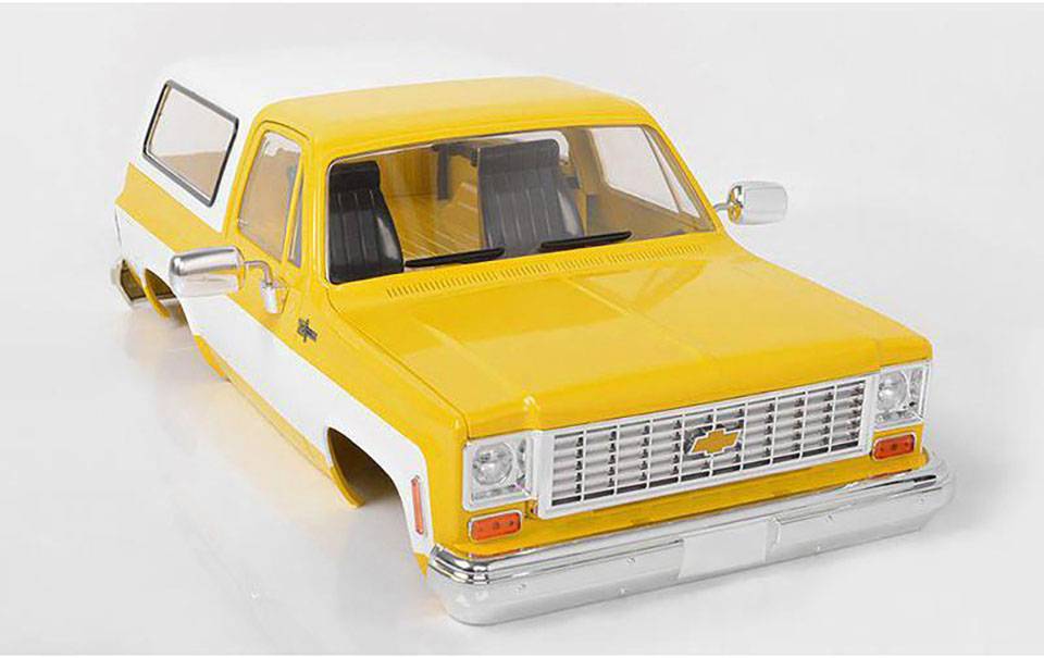 Voiture miniature jaune et blanche de style vintage, avec une calandre argentée et un emblème caractéristique sur le capot.