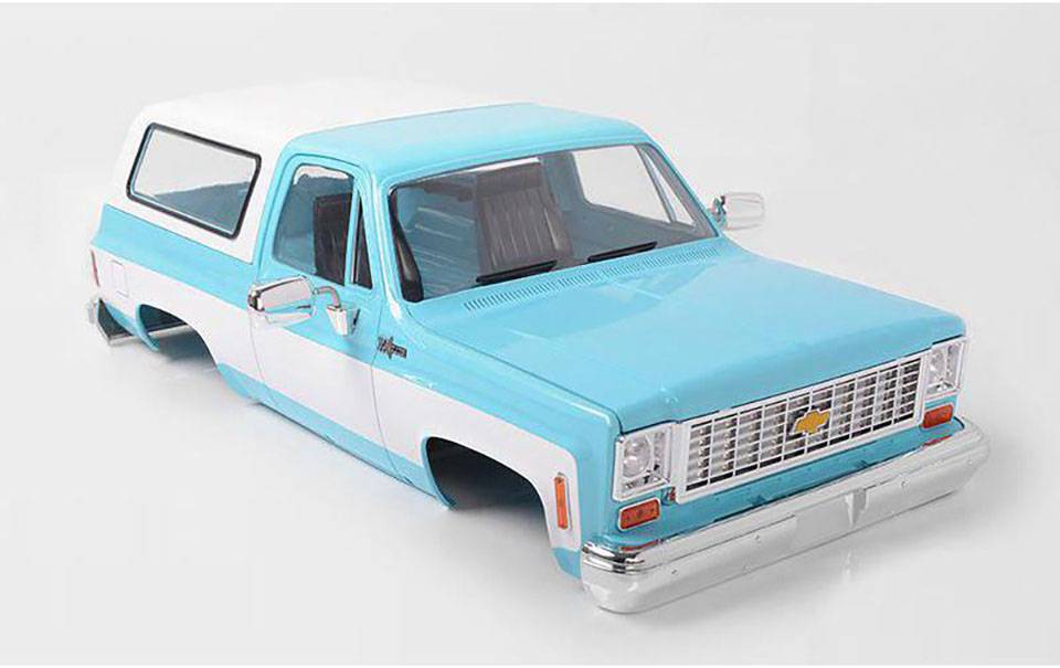Une camionnette tout-terrain vintage à moitié découpée, de couleur turquoise et blanche, sans roues. L'intérieur est vide, et l'arrière-plan est neutre.