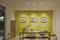 Une salle à manger au design moderne avec une table en bois, des bancs et des images décoratives sur un mur jaune. Une pièce lumineuse agrémentée de plantes.