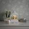 Une lanterne décorative représentant une scène festive est posée sur une table blanche, à côté de deux boîtes-cadeaux et d'un vase de fleurs.