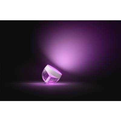 Une petite lampe ronde à boîtier transparent brille d'un rose intense et projette sa lumière sur un fond noir.
