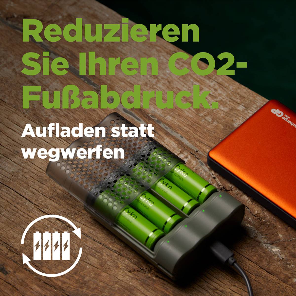 Chargeur avec quatre batteries rechargeables sur une table en bois. Texte : 'Réduisez votre empreinte carbone. Rechargez plutôt que de jeter.'