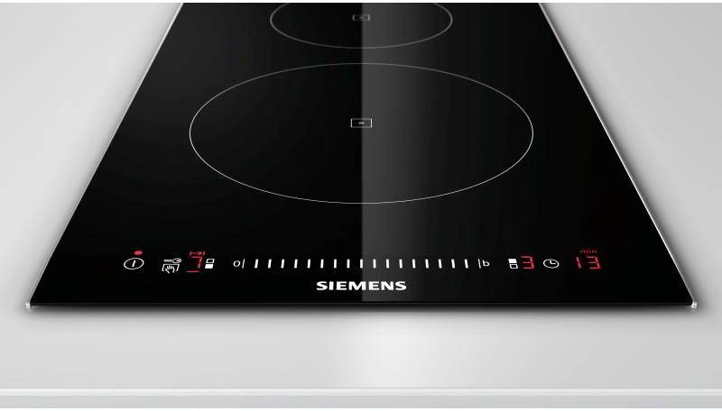 Une plaque de cuisson à induction noire avec deux zones de cuisson, des commandes numériques et un affichage de température rouge sur un support argenté.