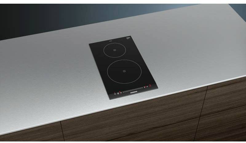 Plaque de cuisson encastrable avec deux plaques rondes sur un meuble en bois style Wagner. Panneaux de commande et symboles sur la façade de la plaque de cuisson.