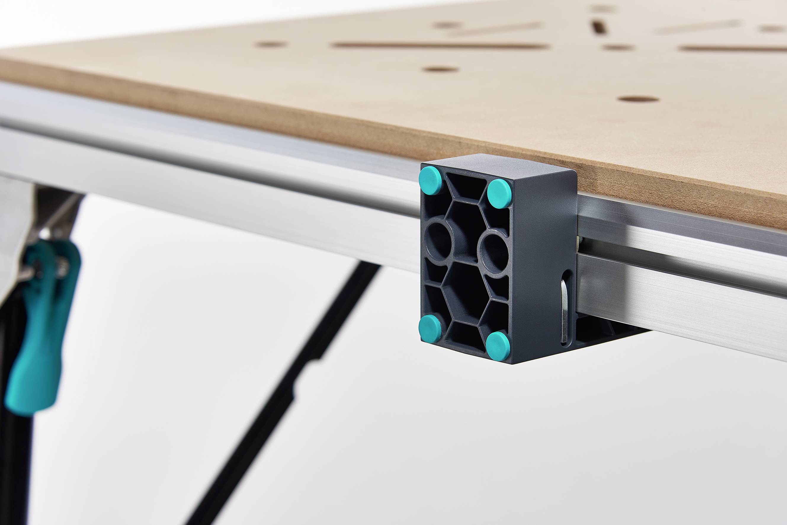 Gros plan sur un clip de bord de table fixé à une table en bois. Le clip présente un motif hexagonal avec des points d'accent turquoise.