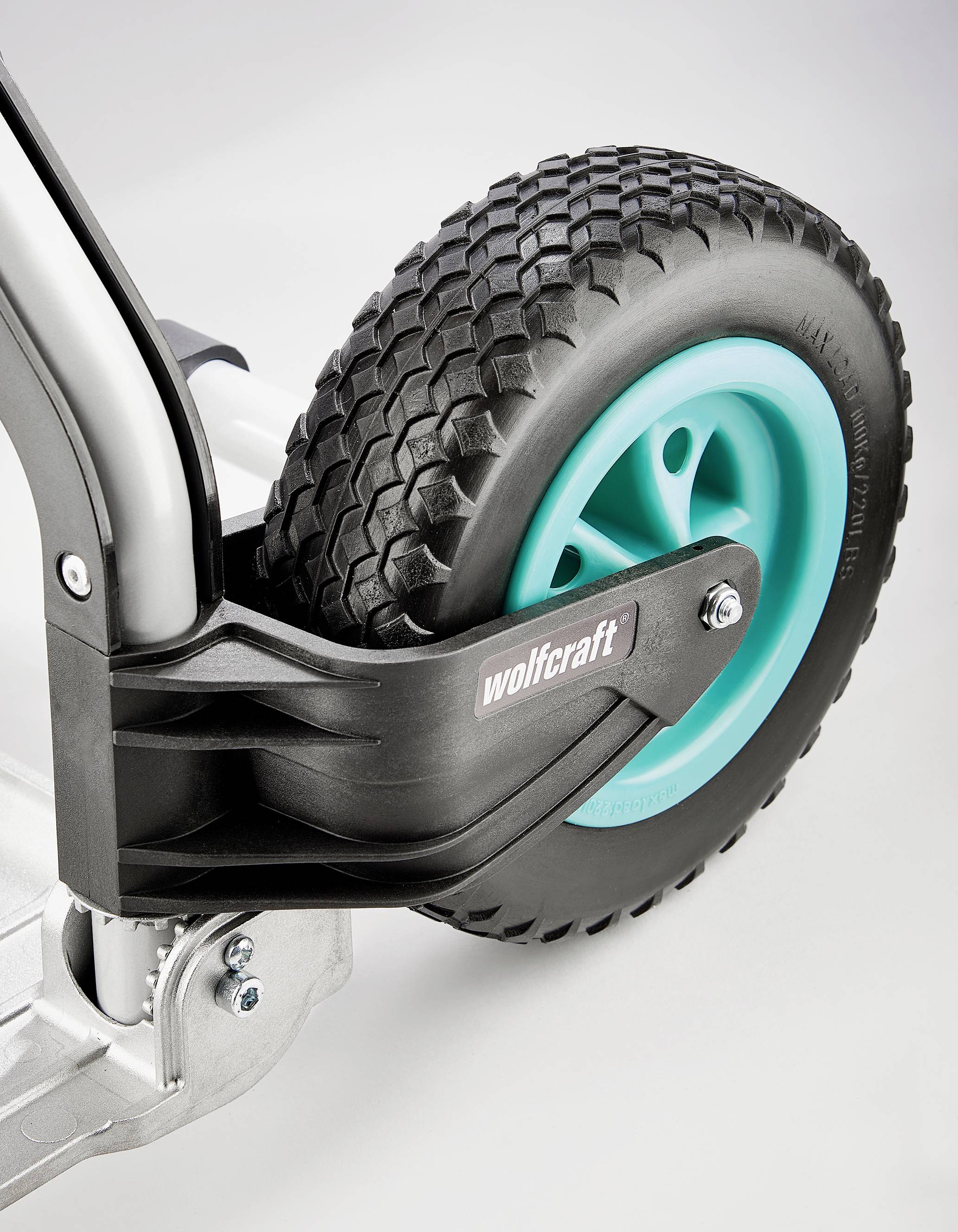 Gros plan d'une roue noire texturée avec un intérieur bleu sur un chariot roulant argenté portant l'inscription 'wolfcraft'.
