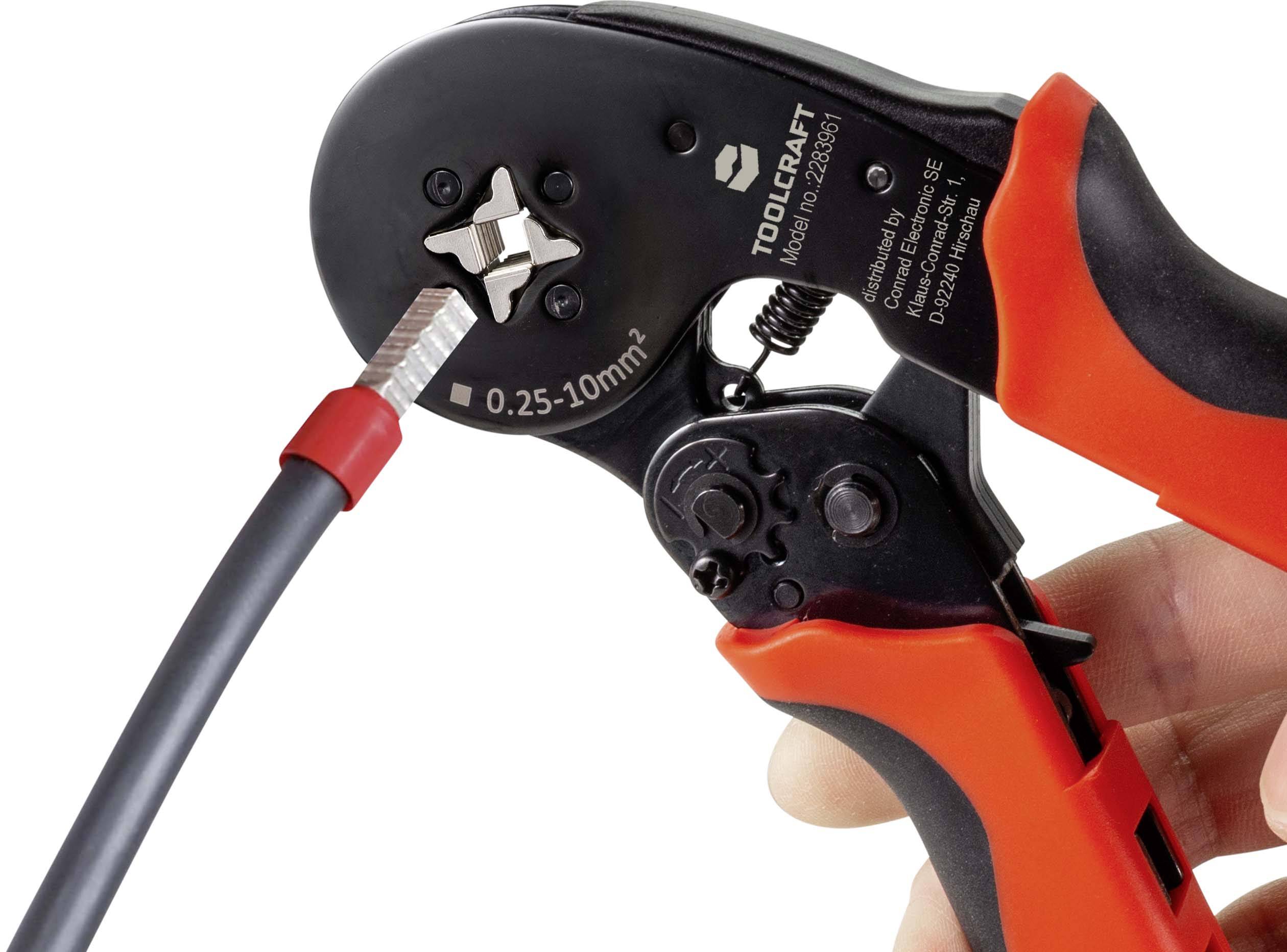 Une main tient une pince à sertir rouge. Elle est utilisée pour sertir un câble avec une connexion métallique.