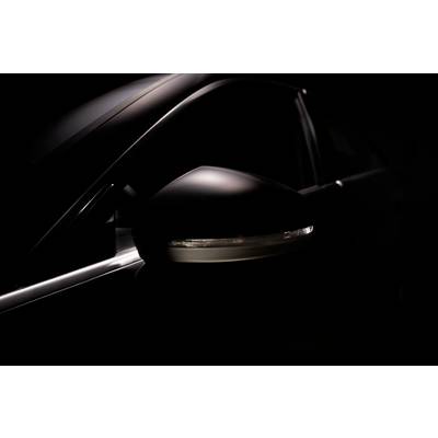 Gros plan sur un rétroviseur de voiture par faible luminosité, révélant le design sombre et les lignes élégantes du véhicule.
