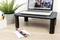 Un ordinateur portable est posé sur un support de table noir. À côté de la table se trouvent un pot avec une plante et des articles de bureau.