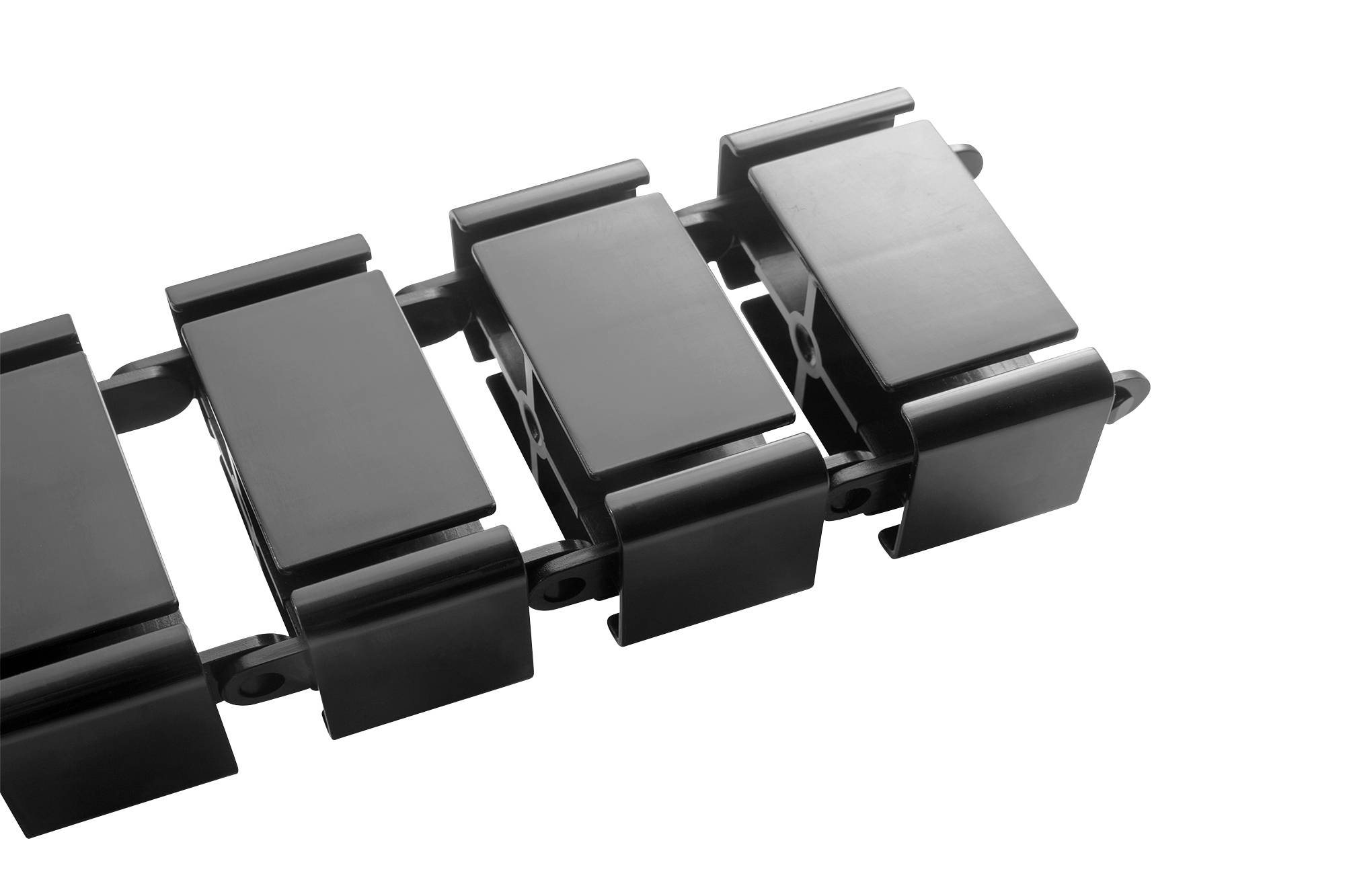 Un gros plan d'un tapis roulant industriel noir montre ses maillons rectangulaires interconnectés.