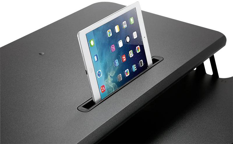 Une tablette avec un menu d'applications ouvert est placée dans une fente sur une table sombre.