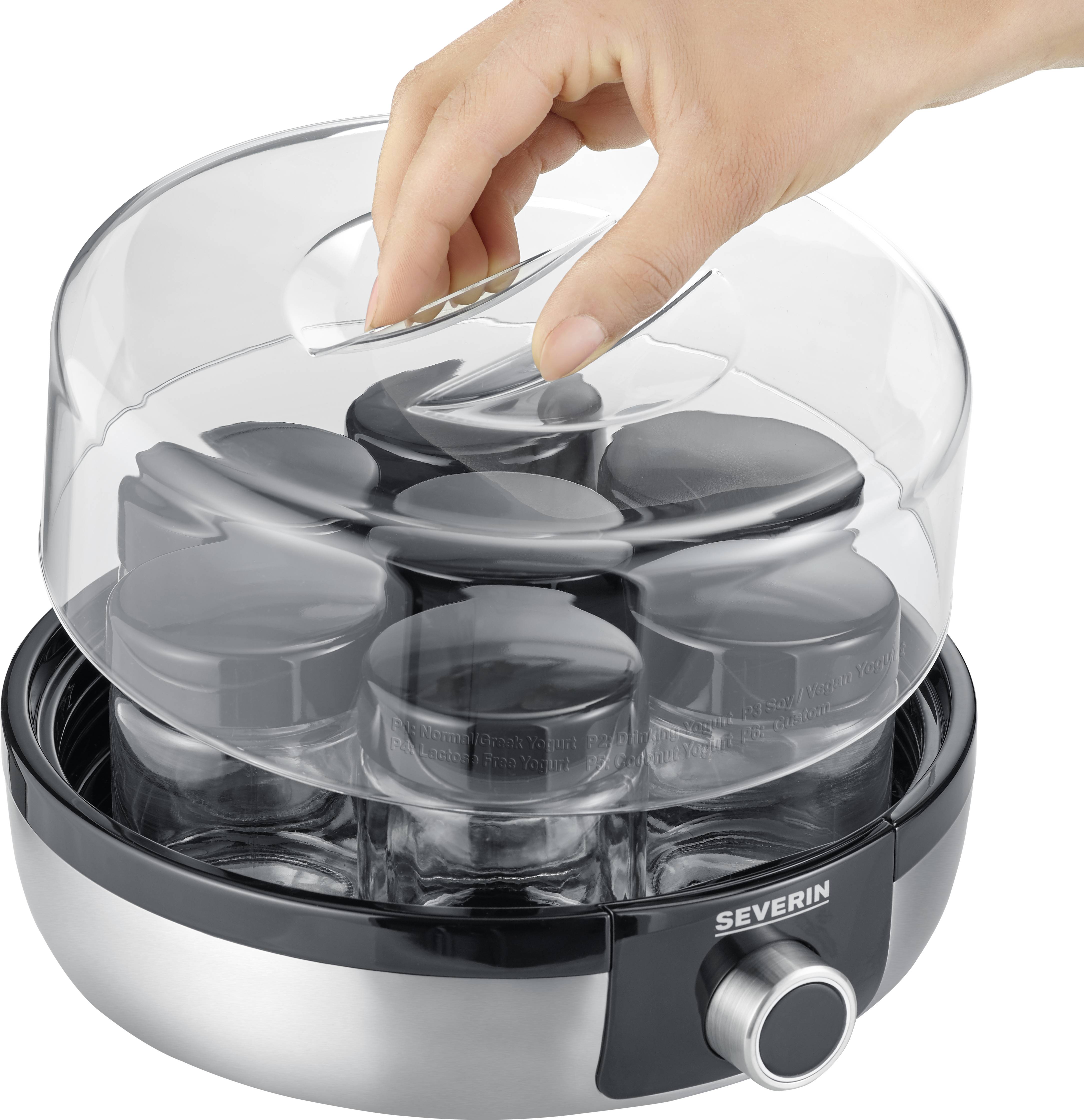 Une main soulève le couvercle d'un yaourtier électrique avec plusieurs petits pots en dessous.
