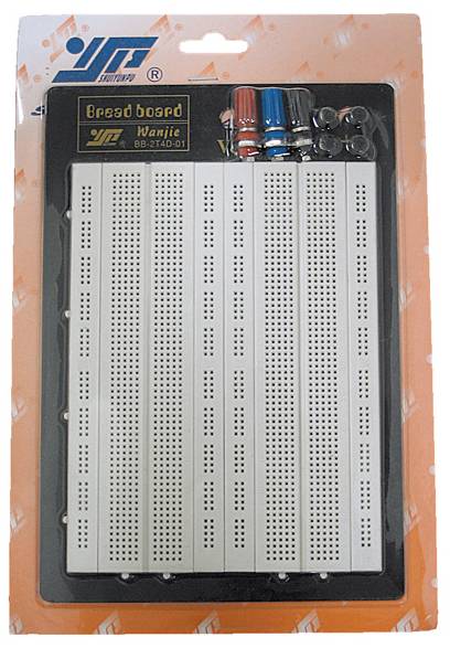 Une platine d'expérimentation (breadboard) dans son emballage. Au-dessus de la platine, plusieurs broches de connexion colorées sont visibles.