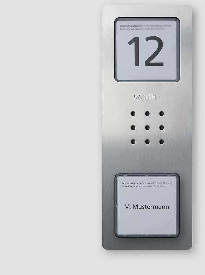 Système d'interphone 'SSS Siedle' avec le numéro '12' et le nom 'M. Dupont'. Surface argentée avec deux zones d'étiquetage et haut-parleur.