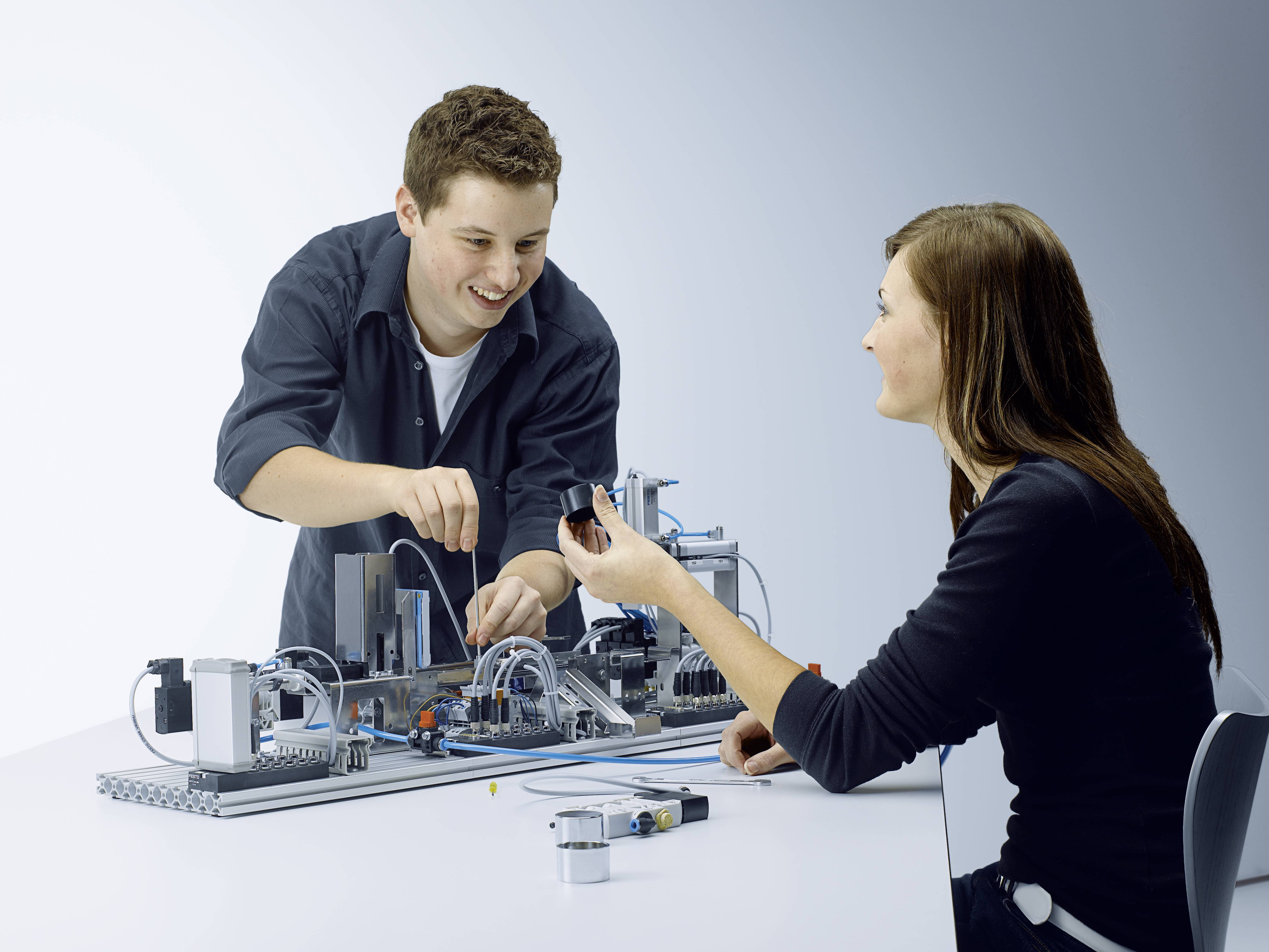 Deux personnes travaillent ensemble sur un projet technique impliquant des composants électroniques posés sur une table.