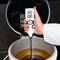 Un thermomètre est plongé dans un liquide et indique 23,2°C. Une personne portant une blouse de laboratoire blanche tient l'appareil.