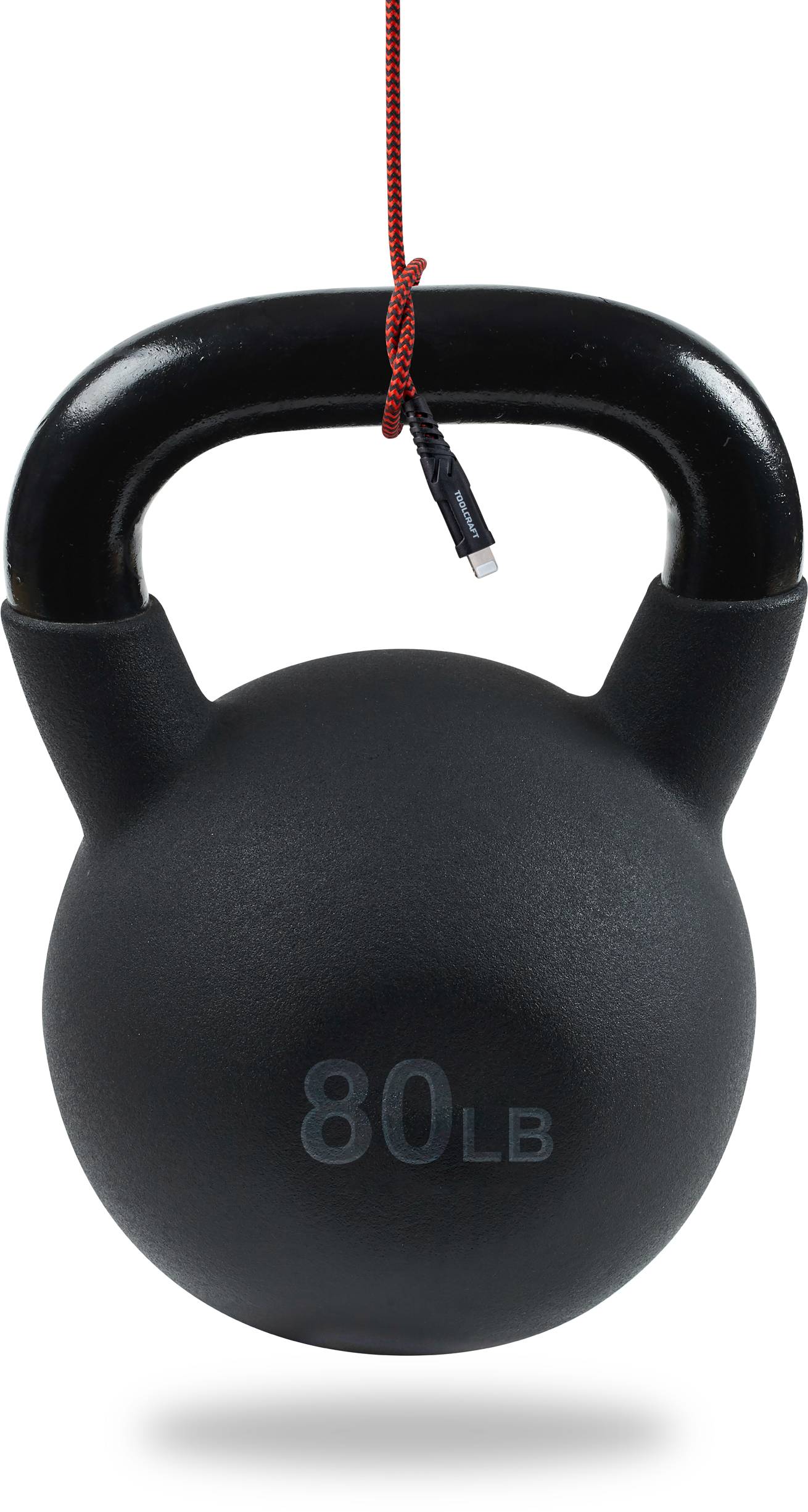 Un kettlebell noir portant l'inscription '80 LB' est suspendu à un câble rouge, flottant dans les airs.
