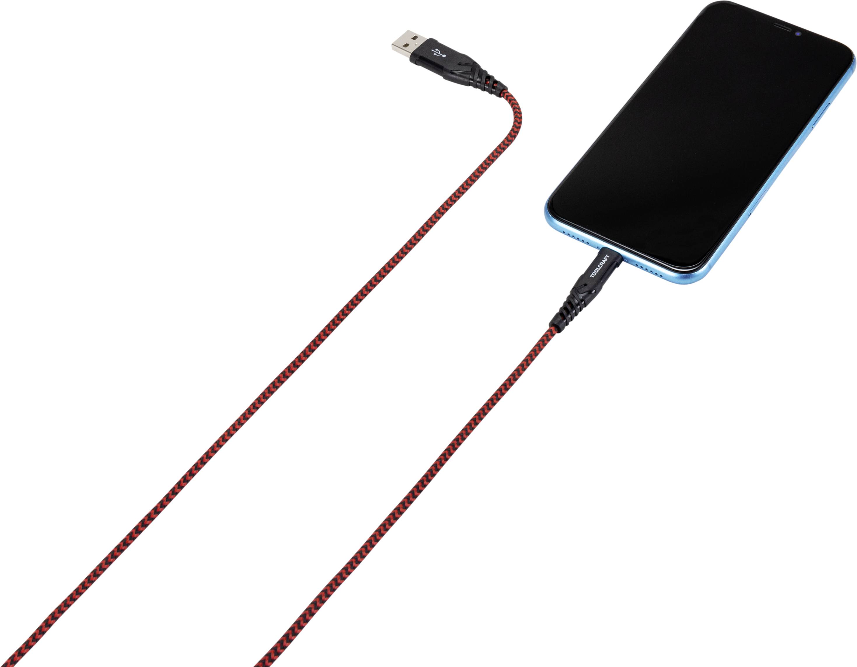 Un smartphone en train d'être chargé via un câble USB tressé rouge. Le câble est branché au téléphone.
