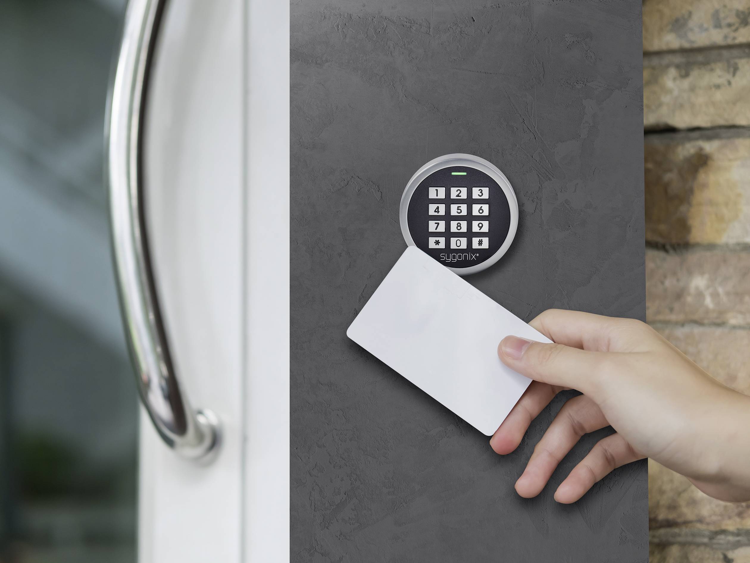 Une main tient une carte d'accès blanche devant un système électronique de contrôle d'accès avec clavier.