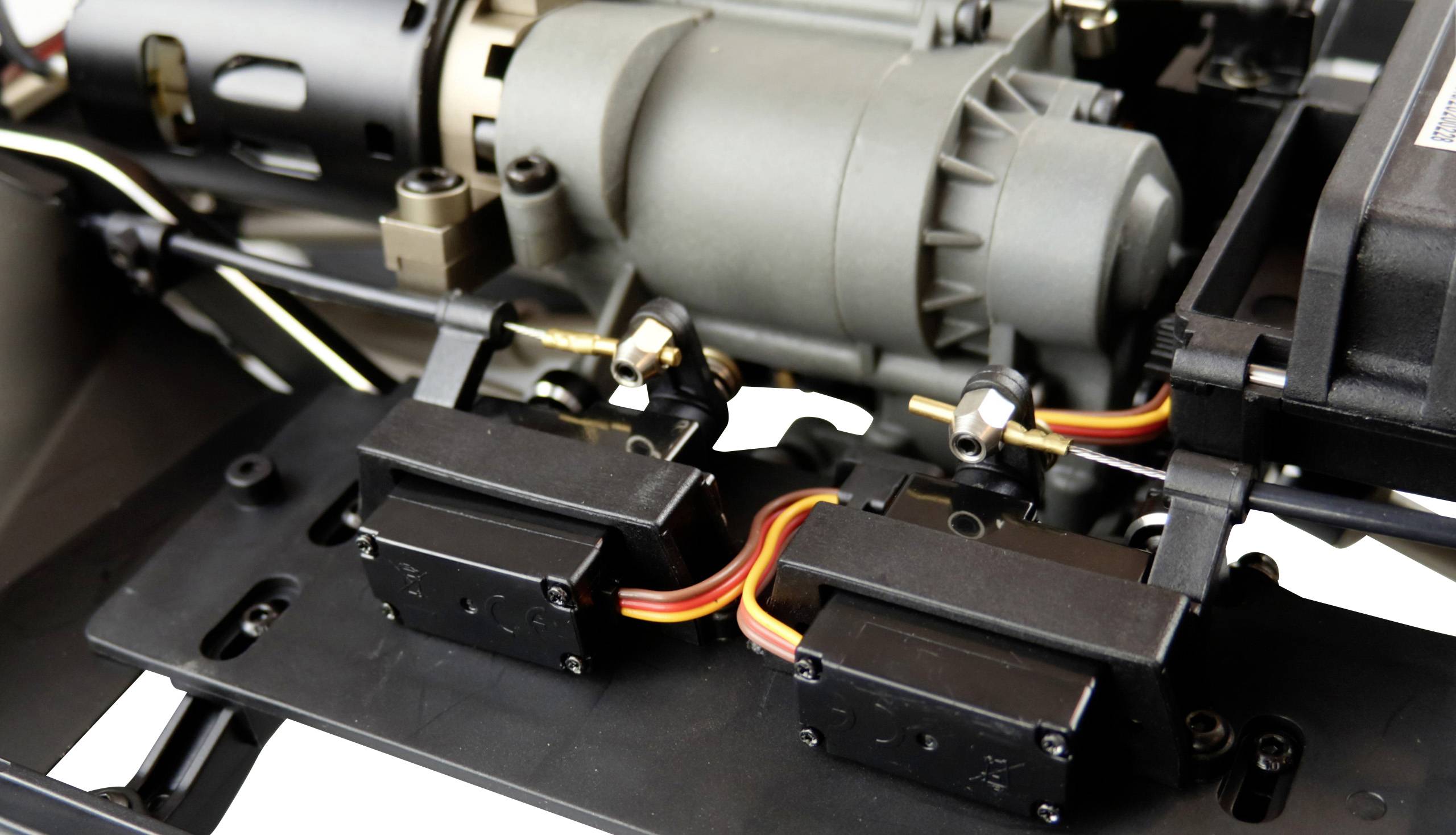 Gros plan d'un système de servomoteurs de modélisme avec des servos interconnectés et des câbles, montés sur une structure mécanique.