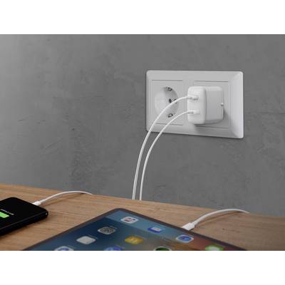 Une table avec un smartphone et une tablette en charge branchés à une prise murale. Les deux appareils sont allumés.