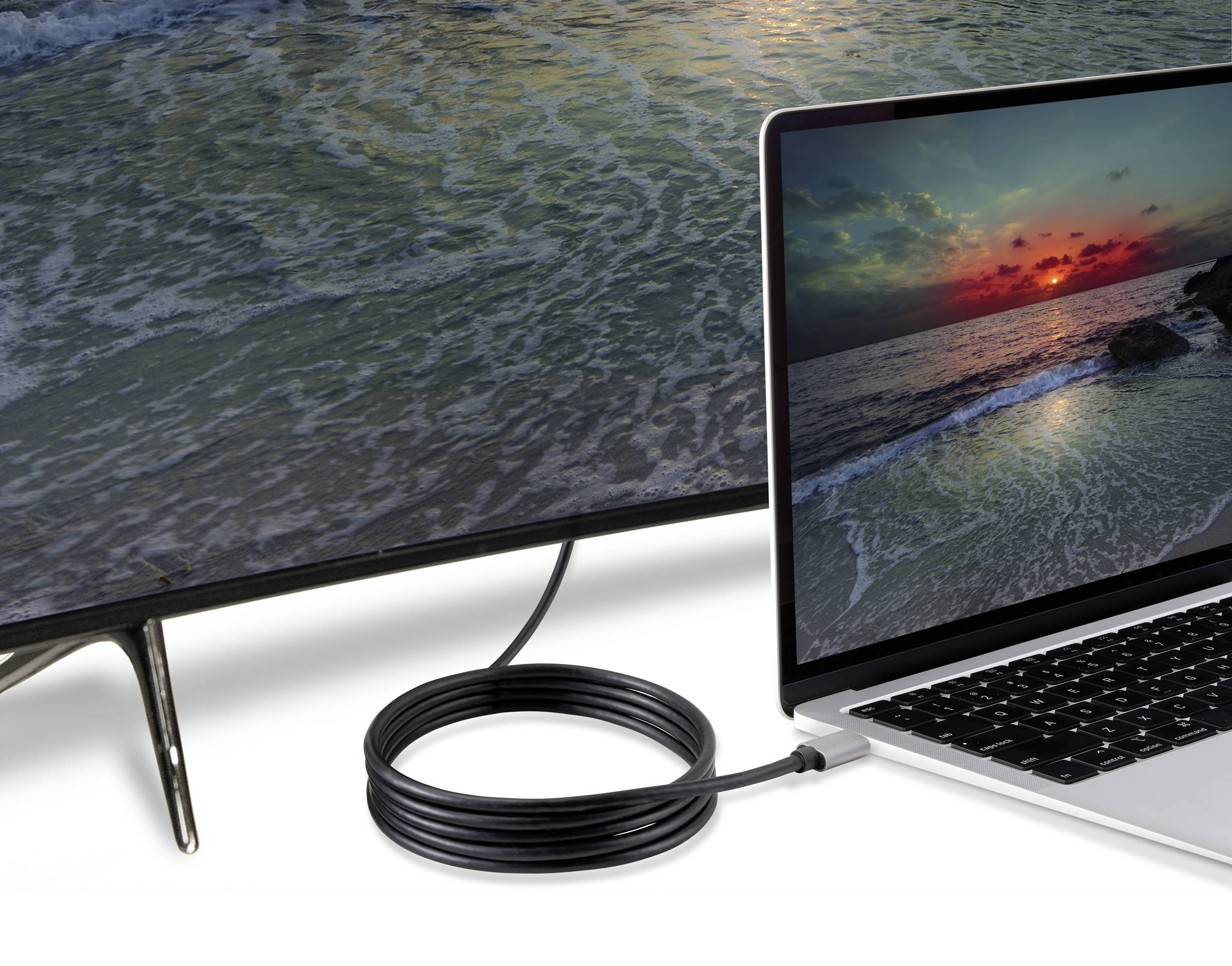 Un ordinateur portable et un téléviseur sont connectés par un câble HDMI, affichant tous deux la même image d'un coucher de soleil sur la mer.