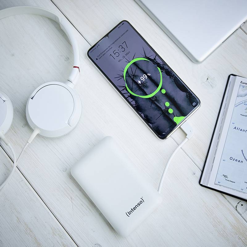 Smartphone avec un écran de chargement vert posé sur une table à côté d'écouteurs, d'une batterie externe et d'un carnet montrant la carte de la Lituanie.