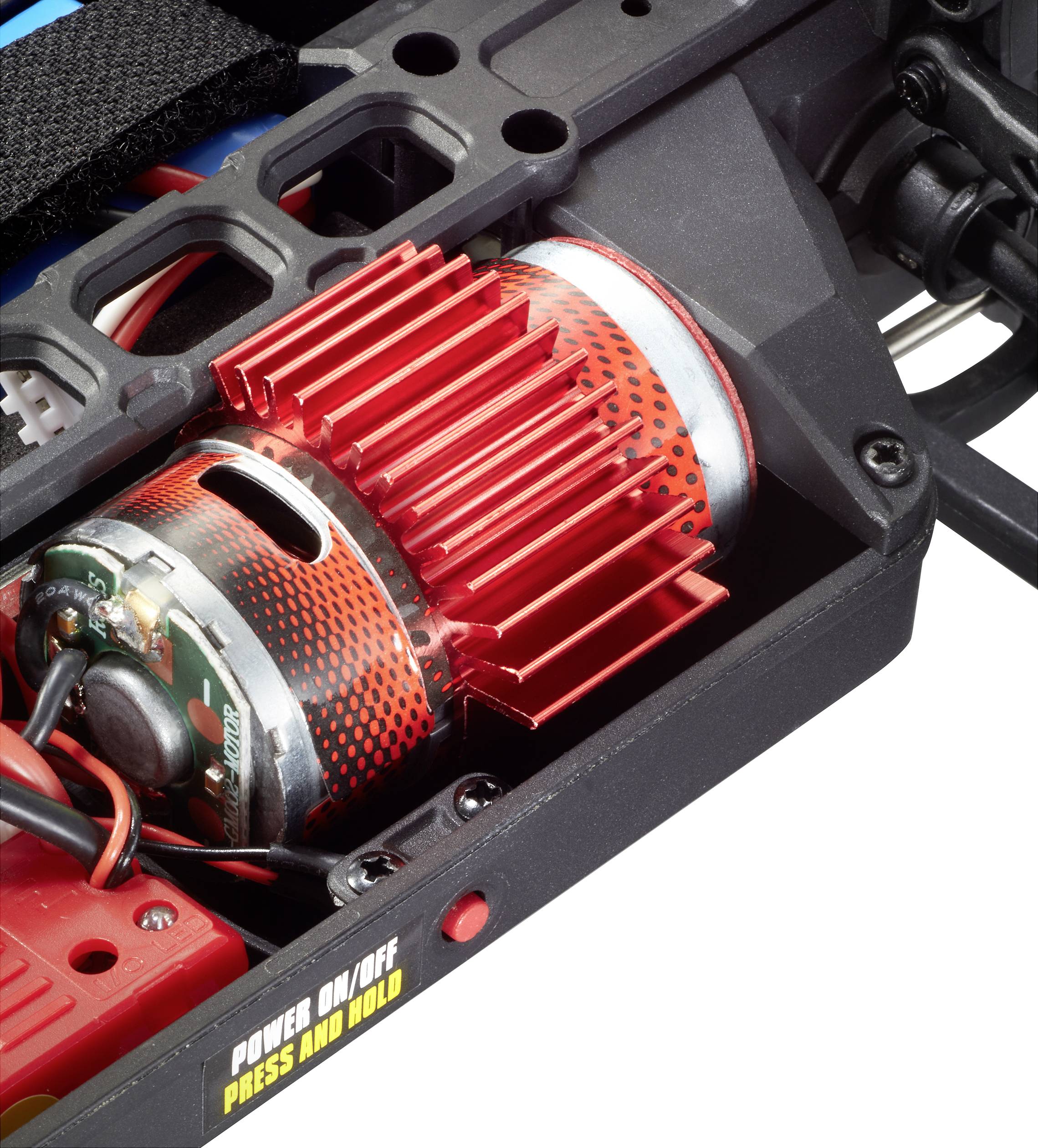 Un moteur électrique avec un dissipateur thermique rouge dans un dispositif technique. Un interrupteur portant l'inscription « MARCHE/ARRÊT APPUYER ET MAINTENIR ».