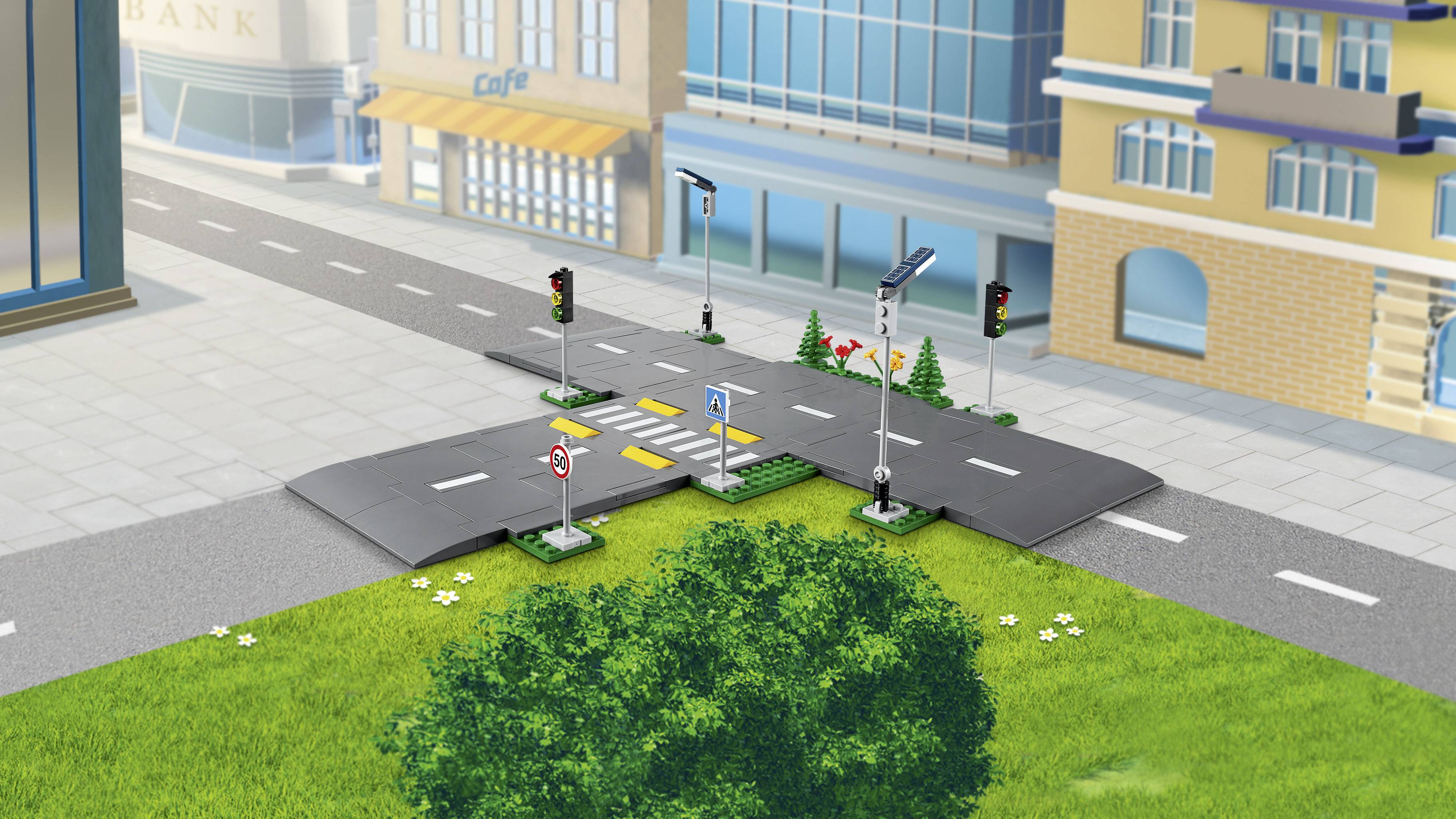 Une ville miniature avec un carrefour, des feux de signalisation et un passage piéton, entourée de bâtiments et d'espaces verts en premier plan.