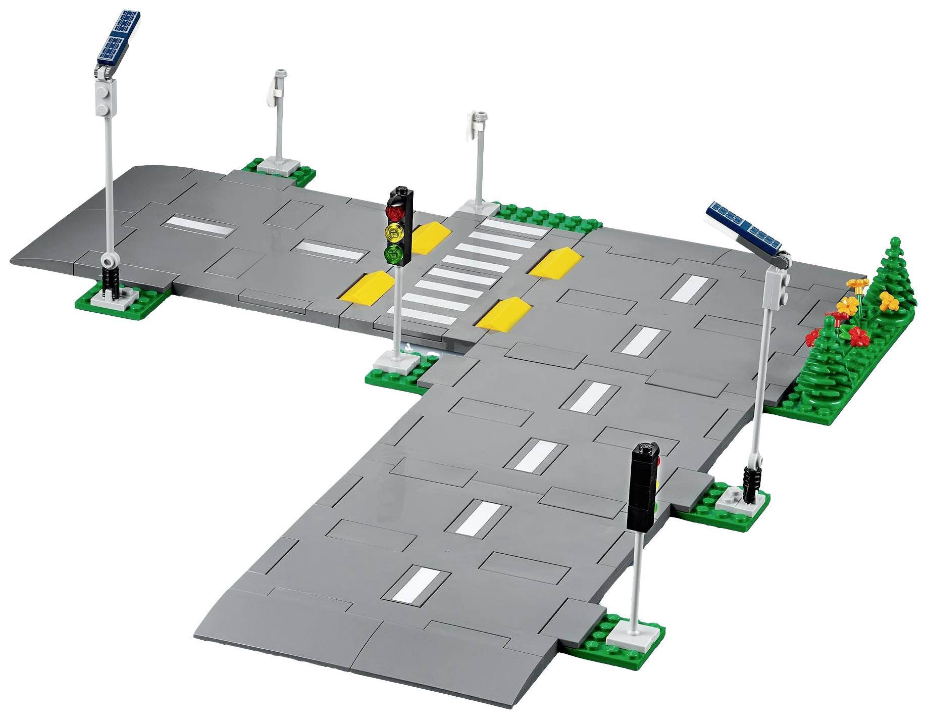 Croisement LEGO avec feux de signalisation et passage piéton, bordé à gauche d'un espace vert. Représentation jouet d'une scène de rue typique.