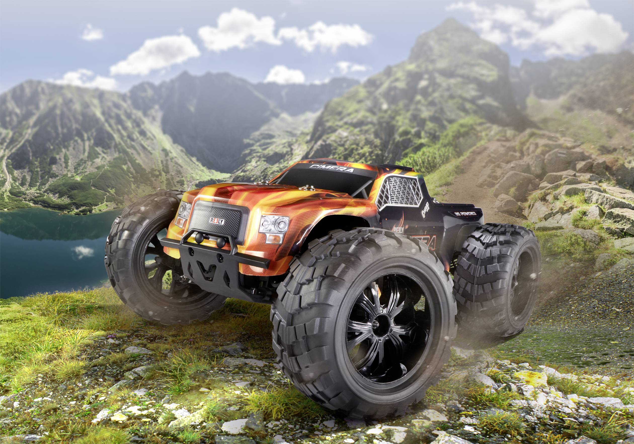 Un monster truck télécommandé orange et noir roule sur un terrain rocailleux dans un paysage montagneux. De grandes roues soulèvent des nuages de poussière.