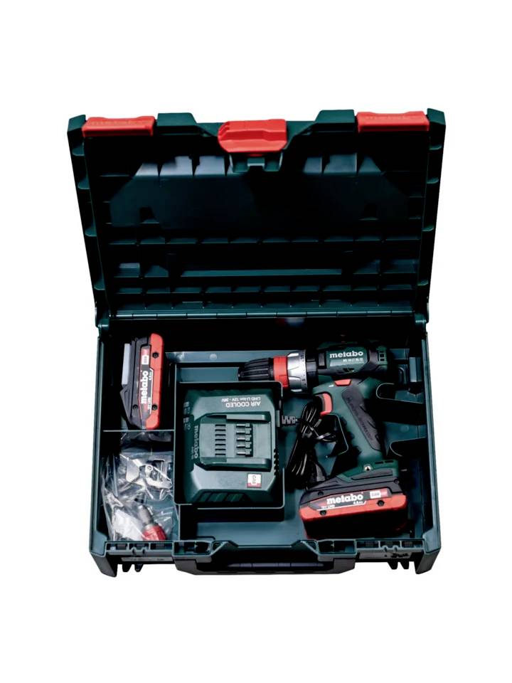 Ensemble de visseuse sans fil dans un coffret ouvert vert, comprenant un chargeur, deux batteries, des embouts de tournevis et des forets.