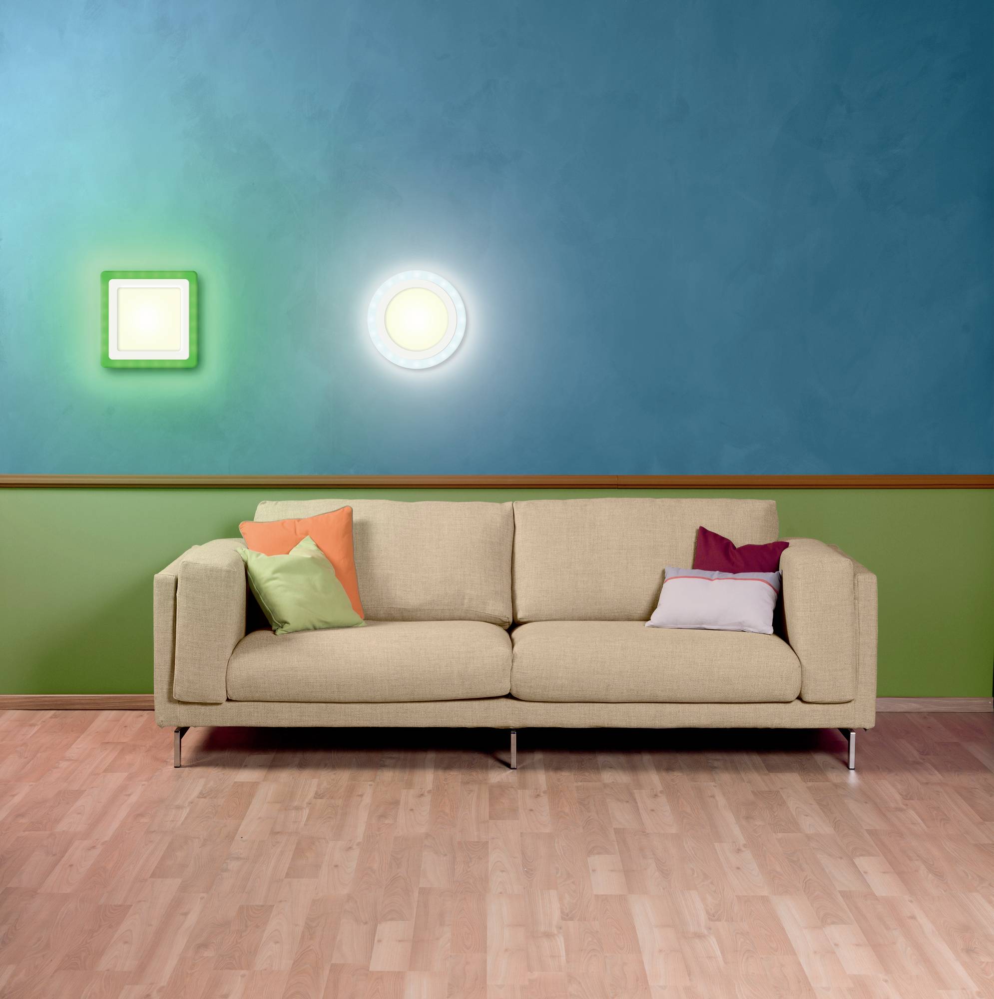 Un canapé beige avec des coussins colorés est posé sur un parquet devant un mur bleu-vert. Deux appliques murales lumineuses sont installées au-dessus.