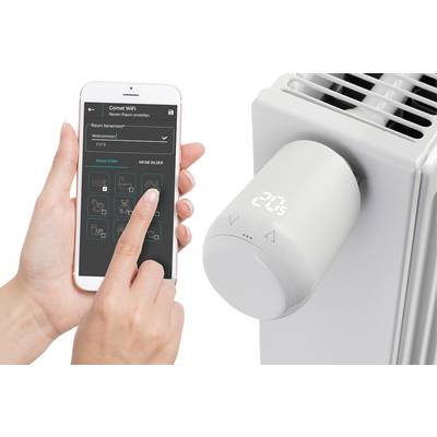 Une main tient un smartphone avec une application de contrôle d'un thermostat de radiateur intelligent, affichant 20°C. Domotique.