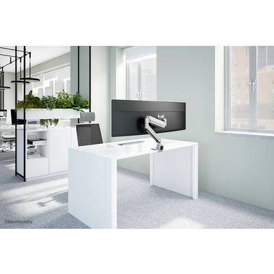 Un espace de bureau moderne avec un bureau blanc sur lequel un grand écran est monté sur un bras ajustable, entouré de plantes.