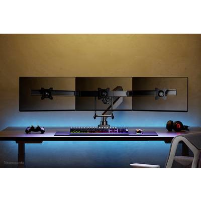 Un bureau avec trois moniteurs sur un support, un clavier RVB, une souris, une manette et un casque audio.
