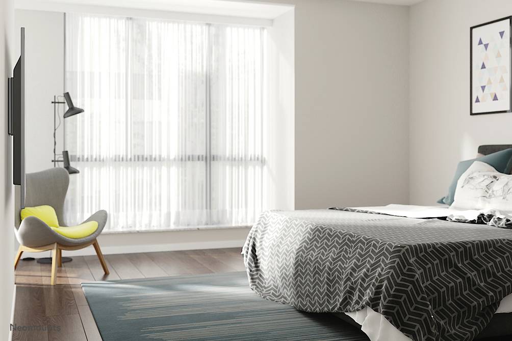 Une chambre moderne avec une grande fenêtre, une housse de lit grise, un fauteuil à côté d'un lampadaire et un tableau accroché au mur.