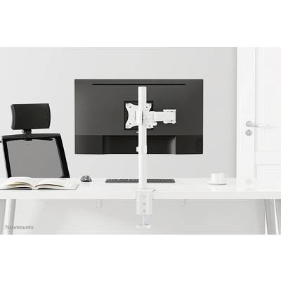 Un espace de travail minimaliste avec un bureau sur lequel un grand écran est posé sur un support blanc, à côté desquels se trouvent une tasse et un livre.