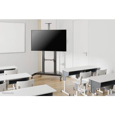 Une salle de classe vide avec plusieurs rangées de tables et un grand écran noir sur un support mobile à l'avant.