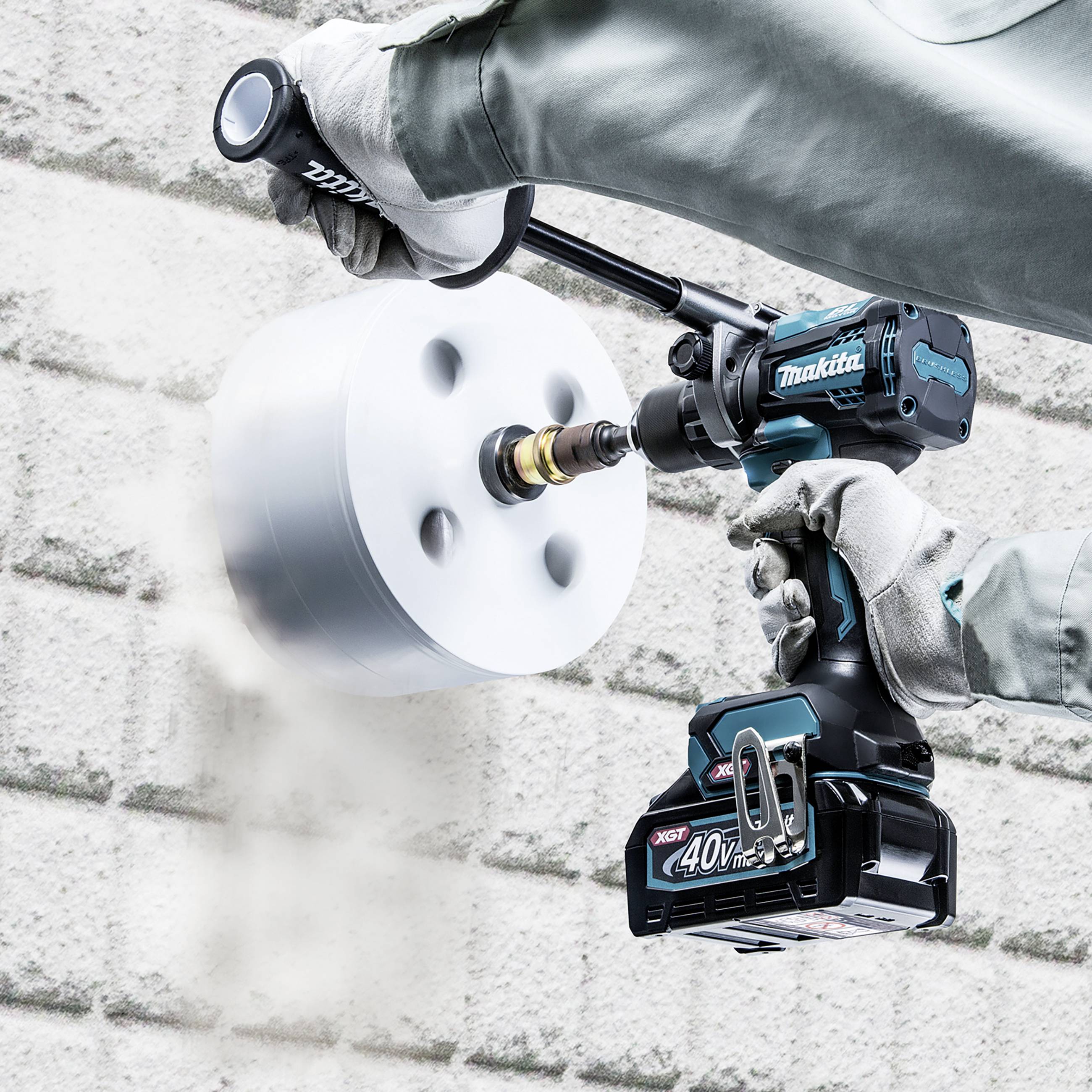 Une personne tient un outil à batterie Makita qui fore un grand trou dans un mur en pierre grise. L'appareil utilise une batterie de 40 V.