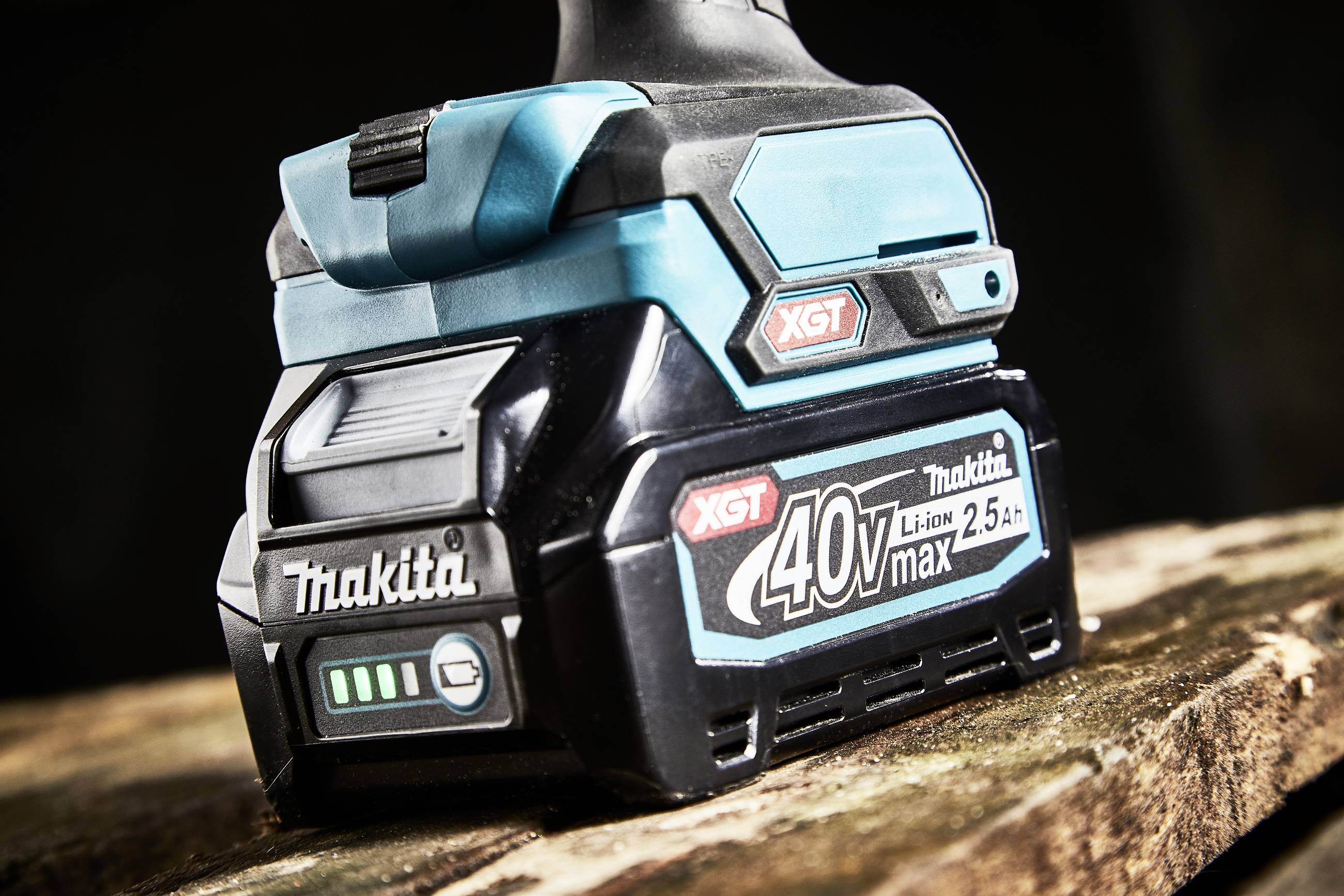 Une batterie portant l'inscription 'Makita XGT 40V max 2.5 Ah' est posée sur une table en bois. La batterie indique un état de charge complet.