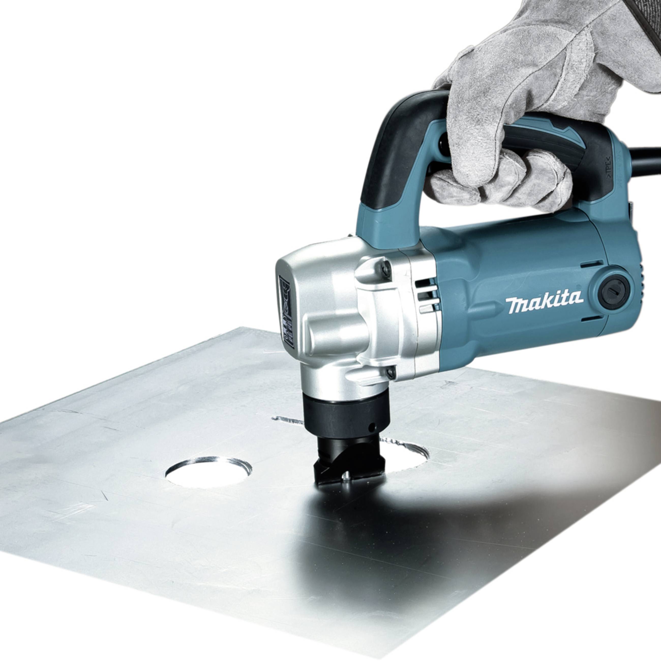 Une personne portant des gants utilise une machine à découper les métaux Makita pour percer des trous précis dans une grande tôle métallique.