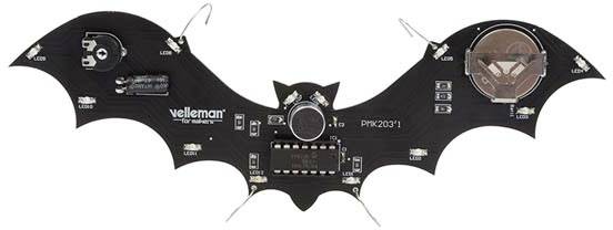 Une carte de circuit imprimé noire, en forme de chauve-souris, avec des composants électroniques, incluant des LED et un compartiment pour batterie, de Velleman.